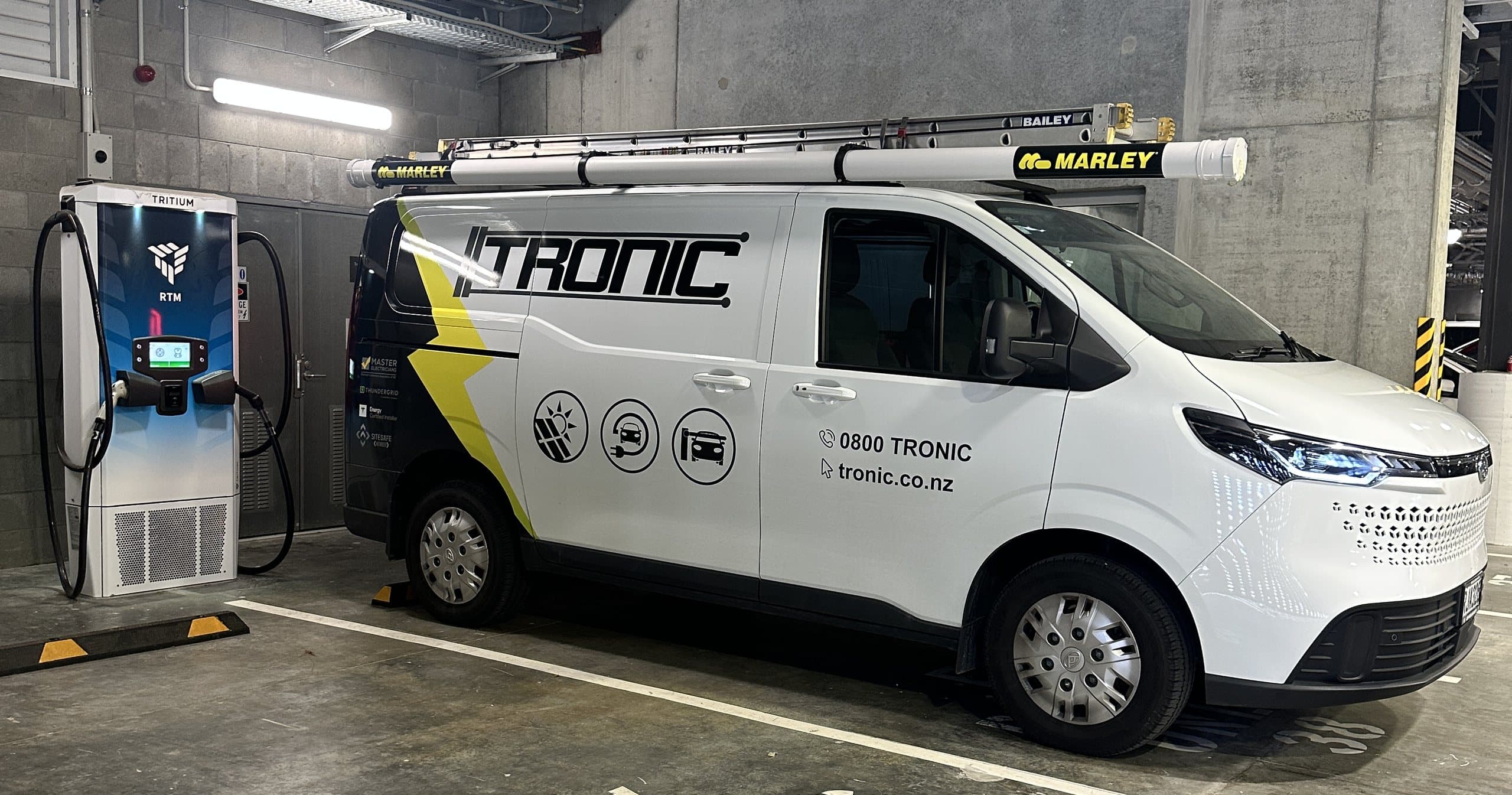 Tronic Electrical van beside a DC fast charger in a basement EV parking bay