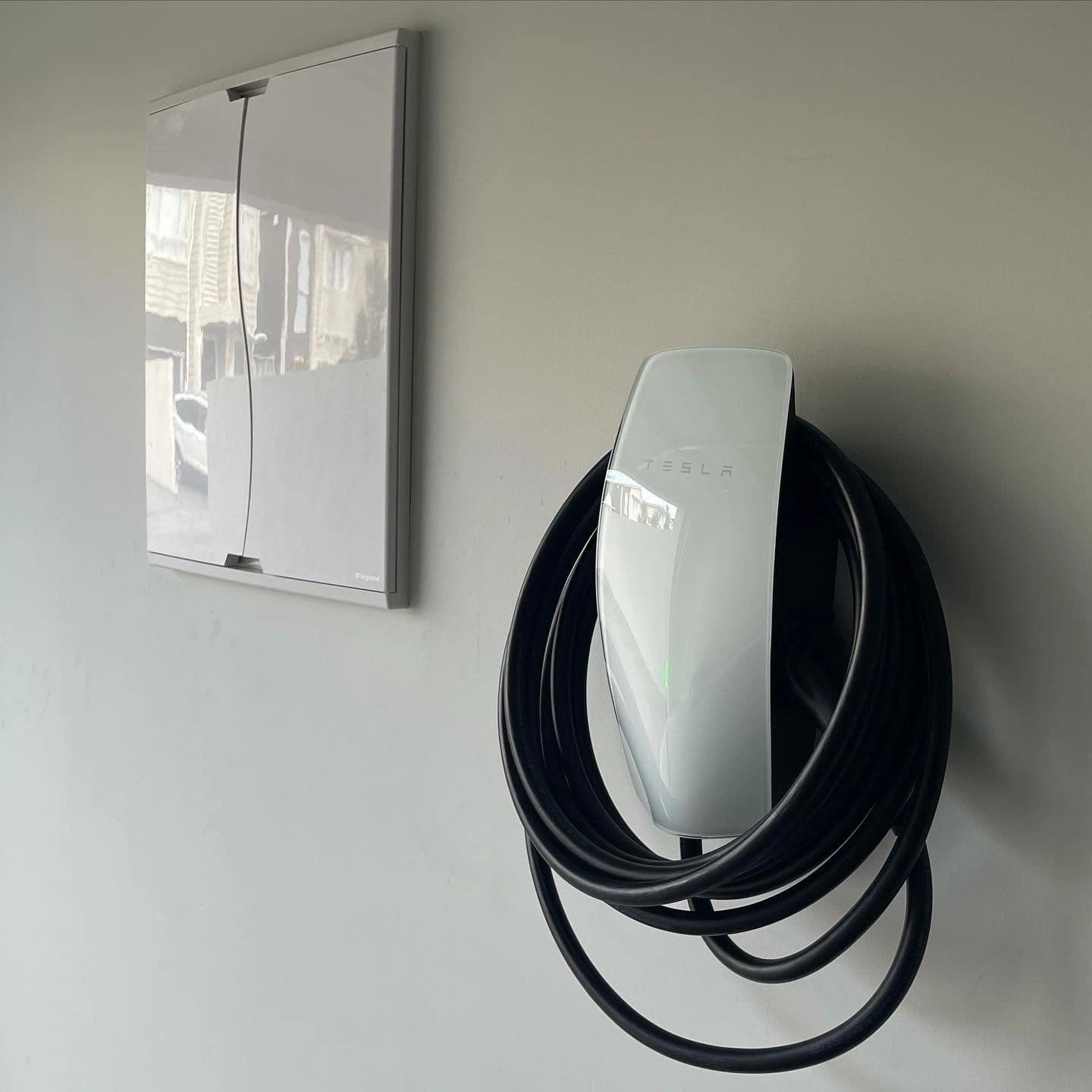 Tronic electrician servicing a wall-mounted EV charger in an Auckland garage