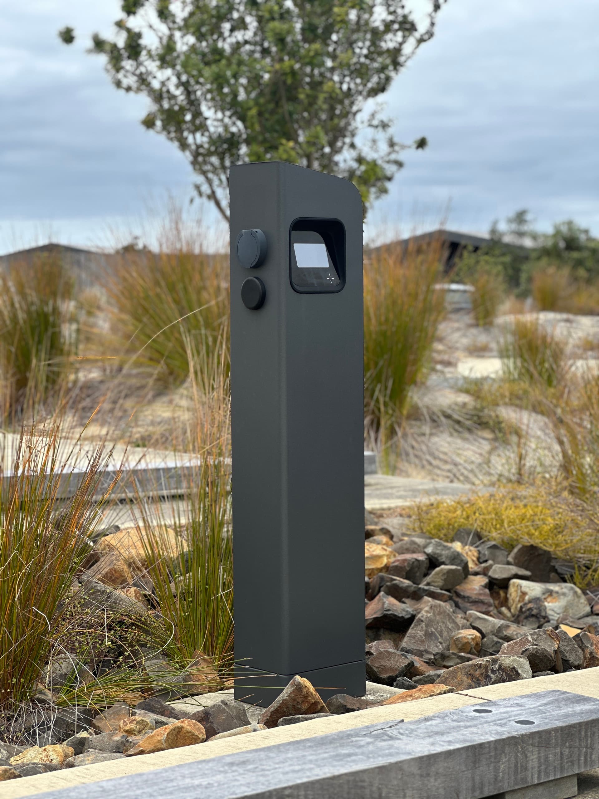 Black bollard EV charger with Type 2 socket in a landscaped public car park
